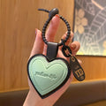 Pink leather heart-shaped car keychain by Trenches of Mariana, personalized men's and women's bag pendant with an intricate face design.