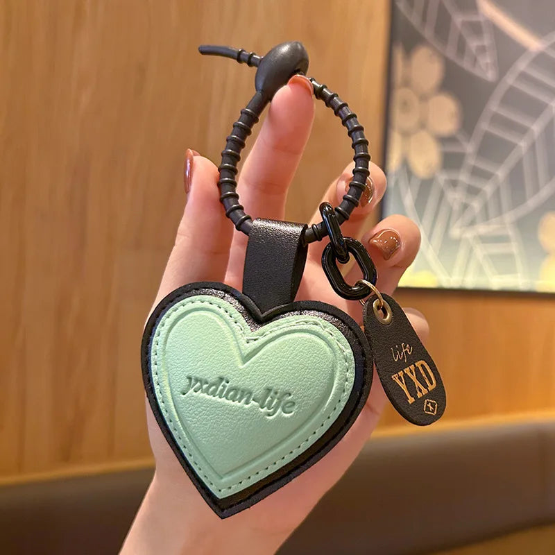 Pink leather heart-shaped car keychain by Trenches of Mariana, personalized men's and women's bag pendant with an intricate face design.