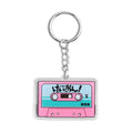 Pink K-On! cassette tape acrylic keychain featuring the HTT band from Japanese anime, attached to a Trenches of Mariana key ring.