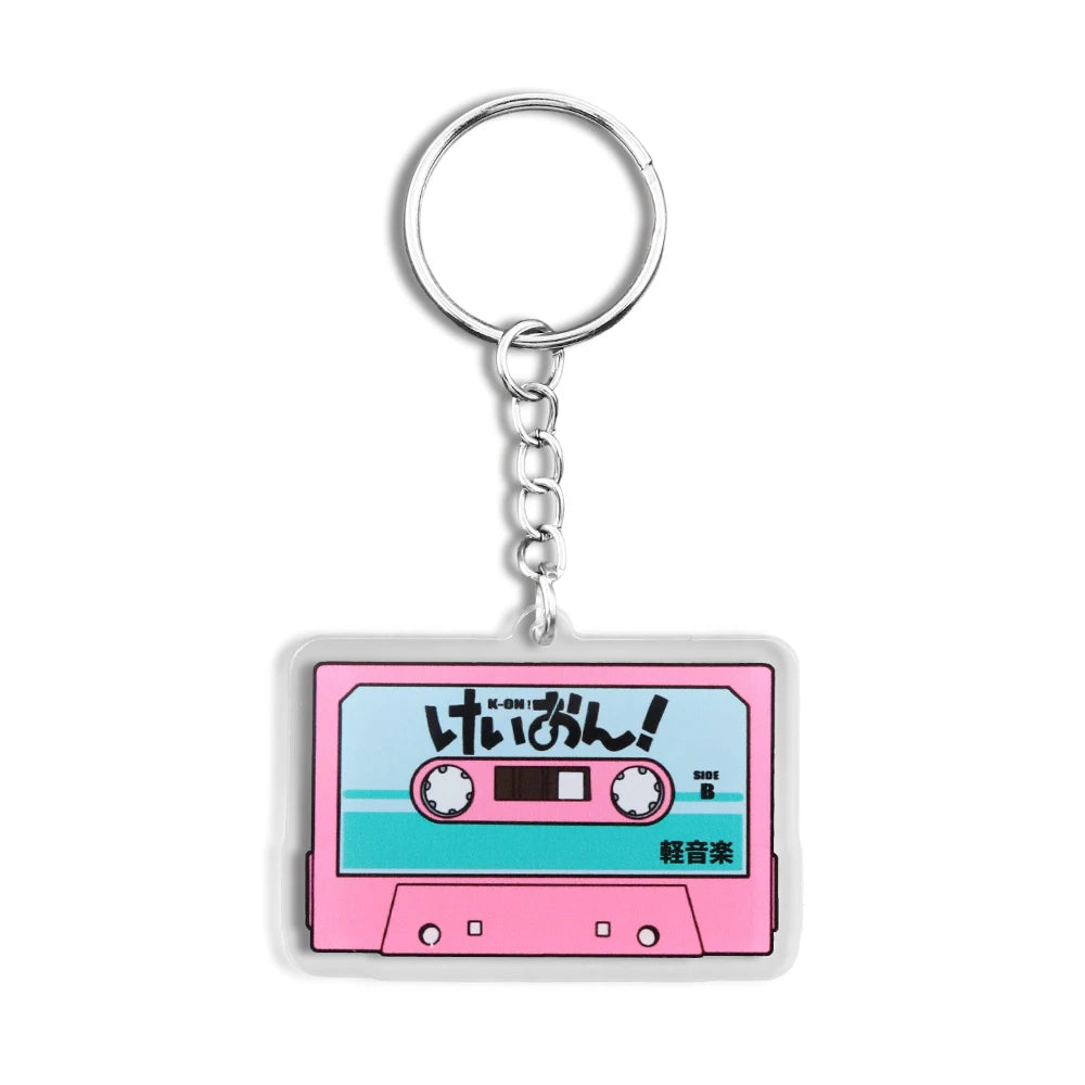 Pink K-On! cassette tape acrylic keychain featuring the HTT band from Japanese anime, attached to a Trenches of Mariana key ring.