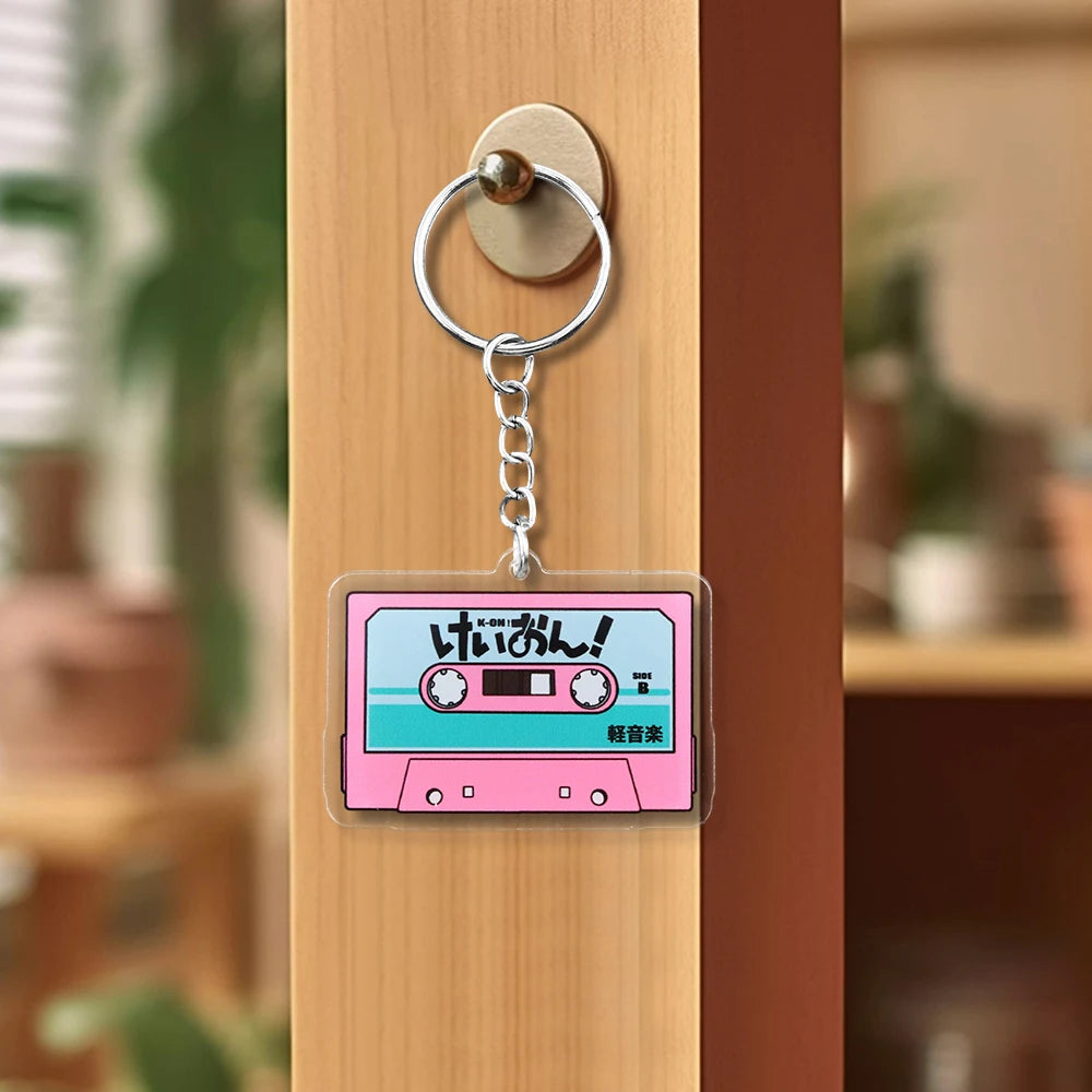 Pink K-On! cassette tape acrylic keychain featuring HTT band logo, anime-themed pendant with Trenches of Mariana branding.