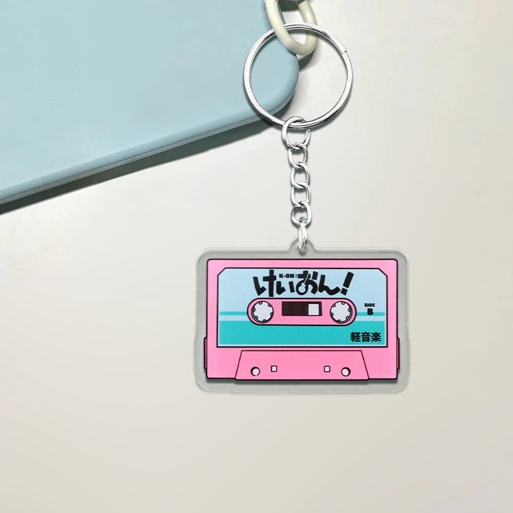 Pink K-On! cassette tape acrylic keychain featuring HTT virtual band, anime-themed pendant with Trenches of Mariana branding